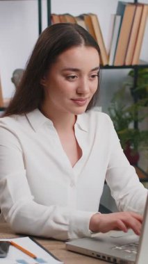 Beyaz bir iş kadını ofis masasında oturuyor ve işini bitirdikten sonra bilgisayarı kapatıyor. İnternet üzerinden çalışan serbest çalışan bir bayan. Defter bilgisayarında e-öğrenme, internette gezinme