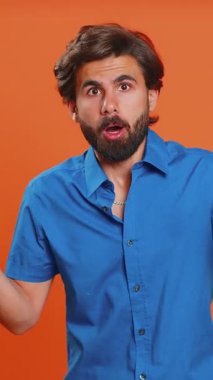 Aman Tanrım, vay canına. Heyecanlı kazanan adam şaşkınlıkla el kaldırıyor büyük gözlerle kameraya bakıyor, ani zaferden şok oluyor. Samimi bir ortadoğulu, turuncu stüdyo arka planında tek başına.