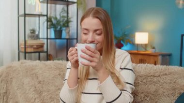 Beyaz bir kadın, elinde sıcak çay fincanıyla evinde oturuyor ve dinleniyor. Sıcak bir içecek, sakin ve rahat bir ortam sağlar. Stres, modern yaşam tarzını rahatlatır. Huzurlu bir ortam.