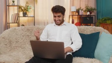 Hintli genç adam dizüstü bilgisayarını mutlu bir gülümsemeyle kapatıyor, zaferi kutluyor başarılı bir görev tamamlanıyor. Kanepede oturan Arap adam verimli bir işten sonra keyfine bakıyor.