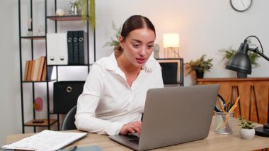 Ofisteki genç iş kadını laptopta teşekkür e-postalarını okuyor ağız kapaklarını zevkle kapatıyor ve gülümsüyor. Masadaki serbest yazar kız bugün yapılan dizin işaretleri görevine emoji kaydetti.