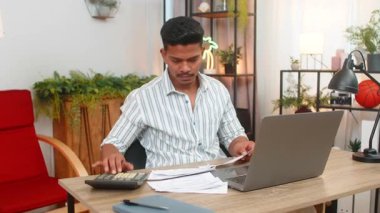 Evdeki Hintli adam dizüstü bilgisayar kullanıyor ve hesap makinesi faturalara giriyor masraflar, bütçeler ve tasarruflar. Masadaki Arap adam makbuzları düzenliyor faturaları kontrol ediyor ve vergi tablosu planlarını kullanıyor bütçeden tasarruf ediyor