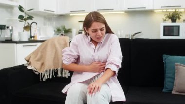 Regl sancısı çeken hasta bir genç kadın, evinde ağrılı bir mide ağrısı. Kanepede karnını tutan bir kız, karın ağrısı ya da regl ağrısı çekiyor. Karın ağrısı, mide iltihabı, ishal, hazımsızlık.