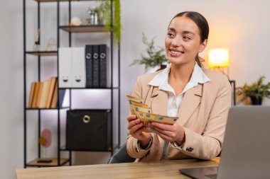 Merkez ofisteki genç iş kadınının elinde avrolar var nakit para sayıyor ve çekler büyük kârla gülüyor. Masadaki serbest çalışan kız gelir için not yazıyor. Güvenli zarfa yığınlar ekliyor ve gelecek tasarruf planları yapıyor.