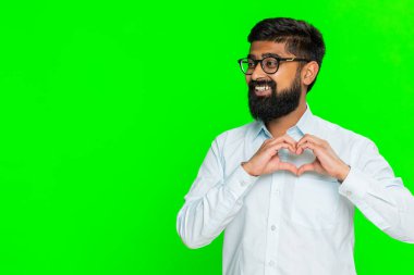 Hintli bir adam kalp şeklini alır. Elleri göğsüne yakındır. Nazikçe gülümser. Yeşil krom anahtar arka planında izole edilmiş Arap bir adam duygusal mesaj gösteriyor.
