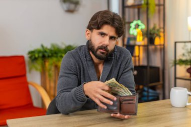 Evdeki Hintli adam cüzdanı açar. Sadece küçük bozuk paralar görür. Faturalar ve düşük maaşlar için endişelenir. Masa başı bütçesi olan Arap bir adam para sayıyor. Fakirlik ve gecikme faturaları hakkında düşünüyor.