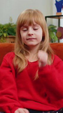 Gibi. Mutlu, beyaz bir kız çocuğu kameraya bakıp olumlu bir işaret veriyor. İyi bir şey, olumlu bir geri bildirim. Oturma odasında oturan genç kız kanepede oturuyor.