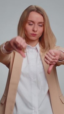 Hoşlanmamak. Takım elbiseli mutsuz ofis kadını işaret dilini gösteriyor, hoşnutsuzluğunu, memnuniyetsizliğini, hoşnutsuzluğunu ifade ediyor. Yetişkin bir iş kadını. Gri arka planda çekilen kapalı stüdyo.