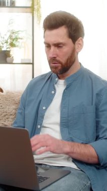 Evde başı dertte olan orta yaşlı bir adam dizüstü bilgisayar ekranına bakarken endişeleniyor. Kanepede oturan beyaz adam, kötü haberlere tepki veriyor ya da hayal kırıklığı ile beklenmedik yüksek harcamalar yapıyor.