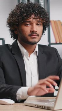 Indian young businessman working on laptop computer shakes finger and saying No be careful scolding and giving advice to avoid danger mistake disapproval sign at home office. Confident freelancer man