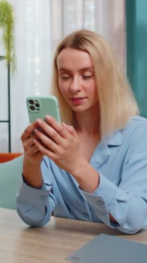 Akıllı telefondan çalışan genç bir iş kadını uzaktan kumandalı iş eğitimi alıyor. Ev ofisinden masada oturuyor. Kız kadın serbest çalışma, e-öğrenme, sosyal medyada mesajlaşma içeriği