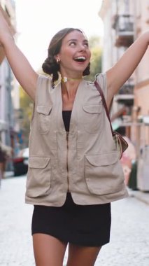 Neşeli gülümseyen, güzel, alışveriş meraklısı genç bir kadın. Açık havada hediye dolu poşetlerle alışveriş yaptıktan sonra. Bayan turist, Summer City caddesi boyunca yürüyor. Kasaba yaşam tarzları