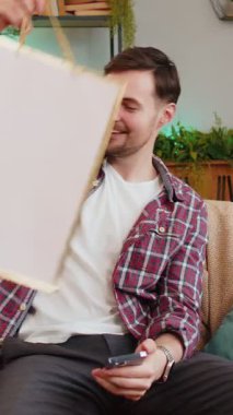 Akıllı telefon kullanan ve evdeki oturma odasındaki kanepede oturan sıradan giysili bir adam. Kuryeden online sipariş aldığına sevinen Kafkasyalı adam çok şaşırdı. İndirimli satış