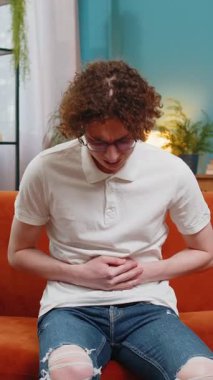 Genç, beyaz bir adam kanepeye uzanmış karın ağrısı ve mide iltihabı şikayeti yaşıyor. Semptom zehirlenmesi geçiren bir adam ishal hazımsızlık peptik ülser pankreatiti geçiriyor..