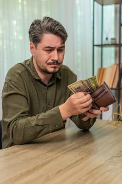 Evdeki zavallı üzgün adam, yoksulluk ve para sıkıntısından endişelenen birkaç nakit para sayıyor. Masadaki genç adam dolarları sınıflandırıyor. Stres korkusu, iflas korkusu, ciddi sorunlar.