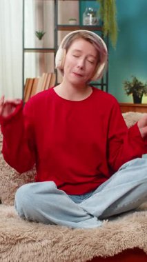 Genç bir kadın evde müzikle mutlu bir şekilde dans ediyor, ellerini ritmik olarak hareket ettiriyor, zevk rahatlığını ifade ediyor. Beyaz kız en sevdiği müzik listesini kablosuz kulaklıkla dinleyip koltukta rahatça oturuyor..