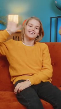 Beyaz çocuk evde mutlu bir şekilde selamlaşırken gülümseyerek el sallıyor. Kanepeye oturur, kameraya bakar, neşeyle merhaba der hoş geldin der ya da elveda der, neşe ve dostluk sergiler.