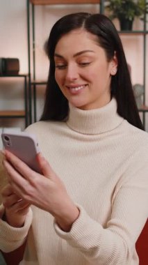 Genç bir kadın evdeki kanepede oturan arkadaşlarıyla internet üzerinden video kamera konuşması yapıyor. Mobil hoparlörden hoşlanan mutlu bayan içeride konuşuyor.