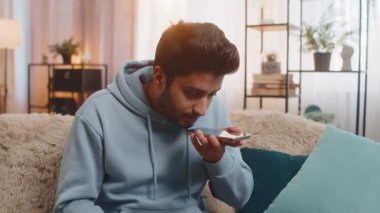 Kızgın kızgın sinirli Hintli genç adam hoparlör moduyla konuşurken tartışıyor sinirden bağırıyor. Hispanik, evdeki oturma odasındaki kanepede oturan memnun olmayan adamı gücendirdi..