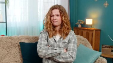 Evde kollarını kavuşturmuş oturan genç bir kadın sinirli ve hayal kırıklığına uğramış görünüyor. Kanepede oturan beyaz saçlı kız öfke, inatçılık, huysuzluk ve hoşnutsuzluğu ifade ediyor.