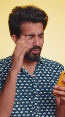 Hintli adam cep telefonu daktilosu kullanıyor. Ani piyango sonuçlarını kaybediyor. Kötü talih, kayıp, başarısızlık. Yakışıklı Hindu çocuk, sarı stüdyo duvarında tek başına, kapalı alanda.