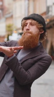 Neşeli, genç ve sakallı adam el hareketleriyle etrafa para saçıyor, daha fazla bahşiş, daha fazla kar, piyango kazanıyor, paylaşıyor, kutluyor. Şehir caddesinde yürüyen kızıl saçlı çocuk.