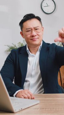 Hoşlanmamak. Ofisteki dizüstü bilgisayarda çalışan Asyalı işadamı hoşnutsuzluğunu, memnuniyetsizliğini ve kötü işini ifade eden işaret hareketini kabul etmiyor. Memnuniyetsizlik ciddi serbest çalışan adam