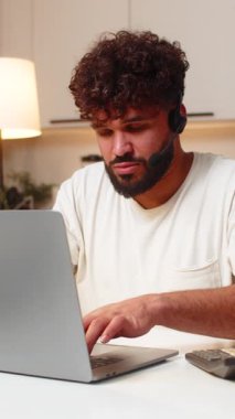 Evde mikrofonlu Arap bir adam müşteriye telefonda ve konuşmada yardım ediyor. Masada oturan genç adam kısa sorular soruyor. Sorunu doğruluyor. Adımları kaydediyor..