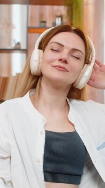 Orta yaşlı bir kadın, kablosuz kulaklıkla müzik dinlerken gözlerini kapayarak kanepeye uzanıyor. Genç yetişkin bir kız, sessiz bir ruh halini benimsiyor, rahatlık, sakinlik ve duygusal rahatlama hissi.