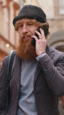 Mutlu sakallı adam telefonda konuşuyor. Şehir caddesinde dolaşan beklenmedik iyi haber dedikoduları. Genç turist çocuk uzaktan iletişim kurarak akıllı telefondan konuşuyor. Şehir yaşam tarzları açık havada