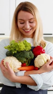 Orta yaşlı bir kadın elinde marketten aldığı sebzelerle elinde keto besiniyle evde gülümsüyor. Akıllı karbonhidrat yiyen genç bir kız evde yemek pişirirken kilo vermeye hazırlanıyor.