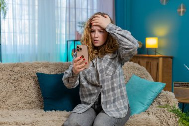 Elinde cep telefonu olan genç bir kadın kötü haber okuduktan sonra üzgün ve hayal kırıklığına uğramış. Kanepedeki beyaz saçlı kız hayal kırıklığına uğramış görünüyor, duygusal tepki, duygusal ifade