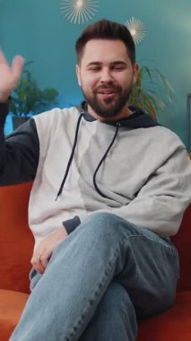 Hoş geldiniz. Beyaz tenli yakışıklı adam kameraya gülümsüyor ve el sallıyor merhaba, merhaba, merhaba ya da güle güle, evde misafirperver bir yüz ifadesiyle karşılıyor. Çocuk oturma odasında kanepede oturuyor.