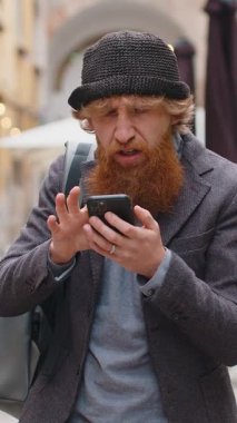 Genç sakallı adam akıllı telefon daktilo kullanıyor. Ani piyango sonuçlarını kaybediyor. Kötü haber, servet kaybı, başarısızlık. Şehir caddesinde yürüyen kızıl saçlı çocuk. Kasaba yaşam tarzları