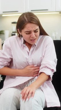 Regl sancısı çeken hasta bir genç kadın, evinde ağrılı bir mide ağrısı. Kanepede karnını tutan bir kız, karın ağrısı ya da regl ağrısı çekiyor. Karın ağrısı, mide iltihabı, ishal, hazımsızlık..