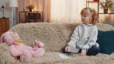 Genç kız, oyuncak pelüş figürleri evdeki kanepenin önüne yerleştiriyor ve basit matematik aritmetiğini tekrarlıyor. Çocuk çocuk ara sıra kahkahalar atar. Sahte otorite tarafından eğlendirilir. Aptal öğretmen rolü.