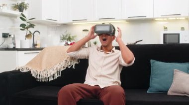 Evde oturan Hintli adam VR kulaklık takıyor. 