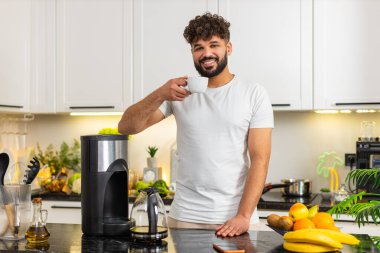 Arap bir adam sabah rutininin erken saatlerinde ev mutfağındaki ottan taze kahveyi fincana koyar. Genç adamın işe odaklanıp tetikte olması için her gün güçlü bir espresso içmesi gerekiyor..