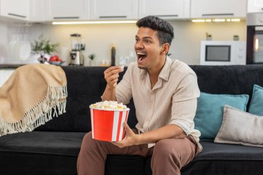 Televizyondaki film fragmanını izleyen Hintli adam patlamış mısır yiyor ve yüz reaksiyonları yapıyor. Kanepedeki Arap adam komik anlar hakkında yorum yapıyor. Bir avuç avuca uzanıyor ve gündelik film izlemekten hoşlanıyor.