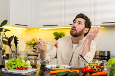 Orta yaşlı bir adam ev mutfağında taze sebze salatası tadıyor ve kendini hayal kırıklığına uğramış hissediyor ve sağlıklı beslenme planını uygulamak zorunda kalıyor. Genç adam iradesini geliştirir ve kilo vermek için sebze seçer..