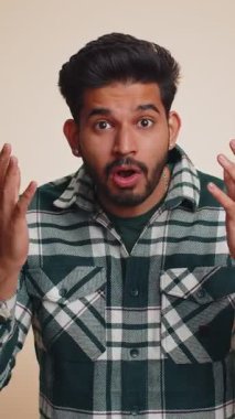 Aman Tanrım, vay canına. Heyecanlı kazanan adam şaşkınlıkla el kaldırıyor büyük gözlerle kameraya bakıyor, ani zaferden şok oluyor. Samimi yakışıklı Hintli çocuk bej renkli stüdyo arka planında tek başına.