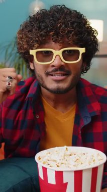 Üç boyutlu gözlüklü heyecanlı Hintli adam kanepede oturup patlamış mısır yiyor ve evde ilginç TV dizileri, spor oyunları, filmler, çevrimiçi sosyal medya filmi içerikleri izliyor. Çocuk eğleniyor.