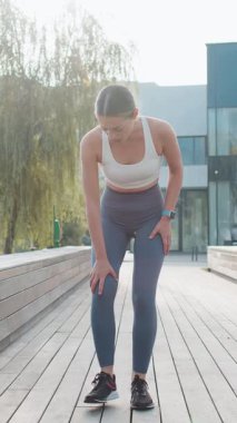 Atletik formda ve kas ağrısı çeken bir kız. Şehir parkında koşarken masaj yapan, travma geçiren genç bir kadın. Fitness dişisinin burkulması şiddetli ağrı germe kuvveti. Bacağa kramp girdi..