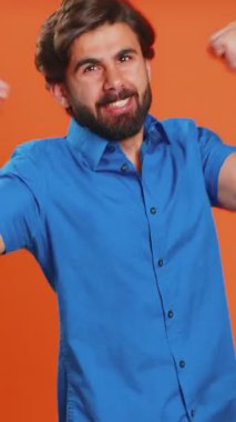 Mutlu, mutlu, gülümseyen adam başarıyı kutluyor, doğum gününü kazanıyor, piyango vurgunu hedefini tutturuyor, oyun oynuyor, iyi haberler, zafer. Turuncu stüdyo arka planında genç bir ortadoğulu.