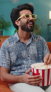 Üç boyutlu gözlüklü heyecanlı Hintli adam kanepede oturup patlamış mısır yiyor ve TV 'de ilginç bir spor maçı izliyor, sosyal medya içerikli çevrimiçi bir film çekiyor. Çocuk eğleniyor.