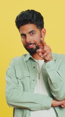 Gözüm üzerinde. Gözlerine ve kamerasına bakan özgüvenli adam, seni birini gözetlerken izlediğimi göster. Yakışıklı, hayal kırıklığına uğramış Hintli adam sarı stüdyo arka planında izole edilmiş.