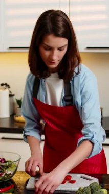 Genç kadın, ev mutfağındaki sebze salatasına domates sosu katıyor. Neşeli yemek hazırlığı yapıyor. Yetişkin kadın sağlıklı besleniyor. Kilo vermek için taze öğle yemeği hazırlıyor. Evde sağlık sorunu yok.