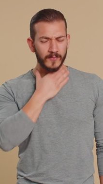 Sağlıksız Lübnanlı genç adam öksürürken elleriyle ağzını kapatıyor kendini kötü hissediyor, alerji ya da viral enfeksiyon belirtileri, enfeksiyon, ağrı, virüs. Orta Doğulu çocuk bej renkli stüdyo arka planında izole edilmiş.