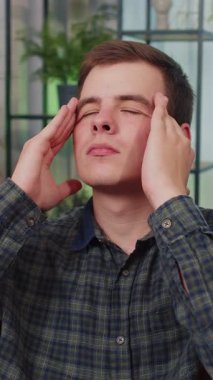 Kafkasyalı bir gencin baş ağrısı, tansiyon, migren, stres, ekşitme, yüksek tansiyon gibi hastalıkları tedavi etmek için tapınakları ovmasından memnun değil. Evdeki kanepede oturan genç adam.