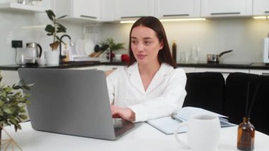 Evde genç bir kadın dizüstü bilgisayarı kapatıyor. Rahatlama gününde gülümseyen gülümsemelere bakıyor. Sakin sakin. Kanepedeki beyaz kız ellerini dizüstü bilgisayarın üstüne koyup hafifçe gülümsüyor..